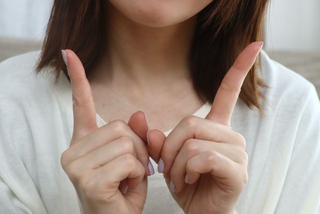 両手のひとさし指を立てる女性の手